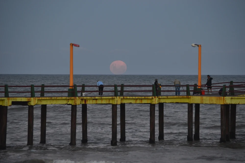 La luna sobre el mar y el muelle